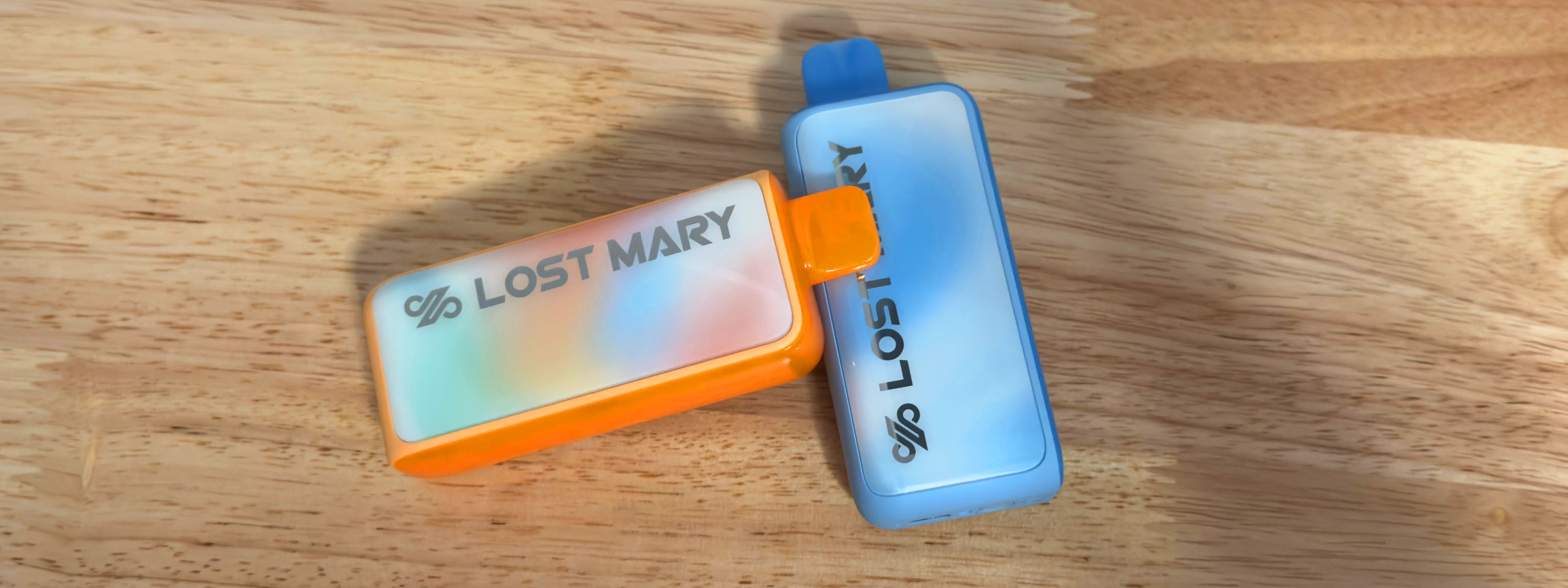 Lost Mary MT35000 Turbo vapes in orange and blue colors displayed side-by-side on a wooden surface.